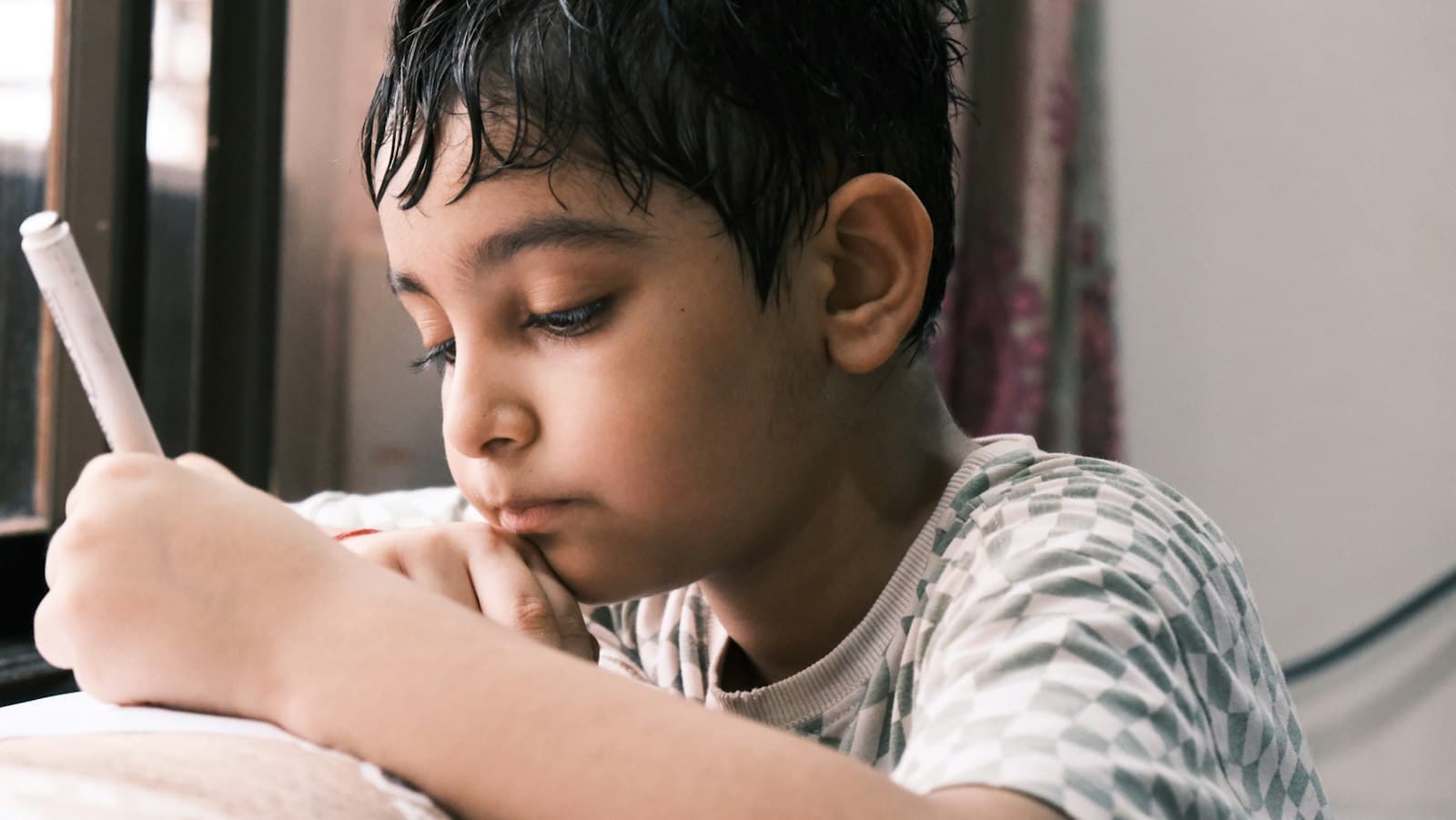 An Indian boy concentrating on his written maths practice at home