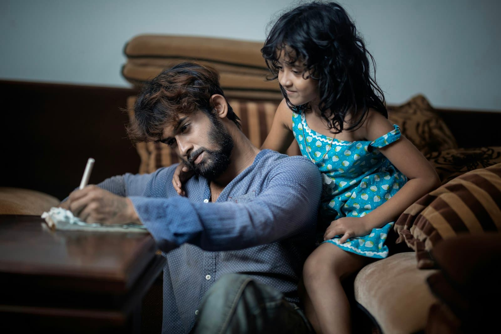 A father going through maths homework with his daughter at home